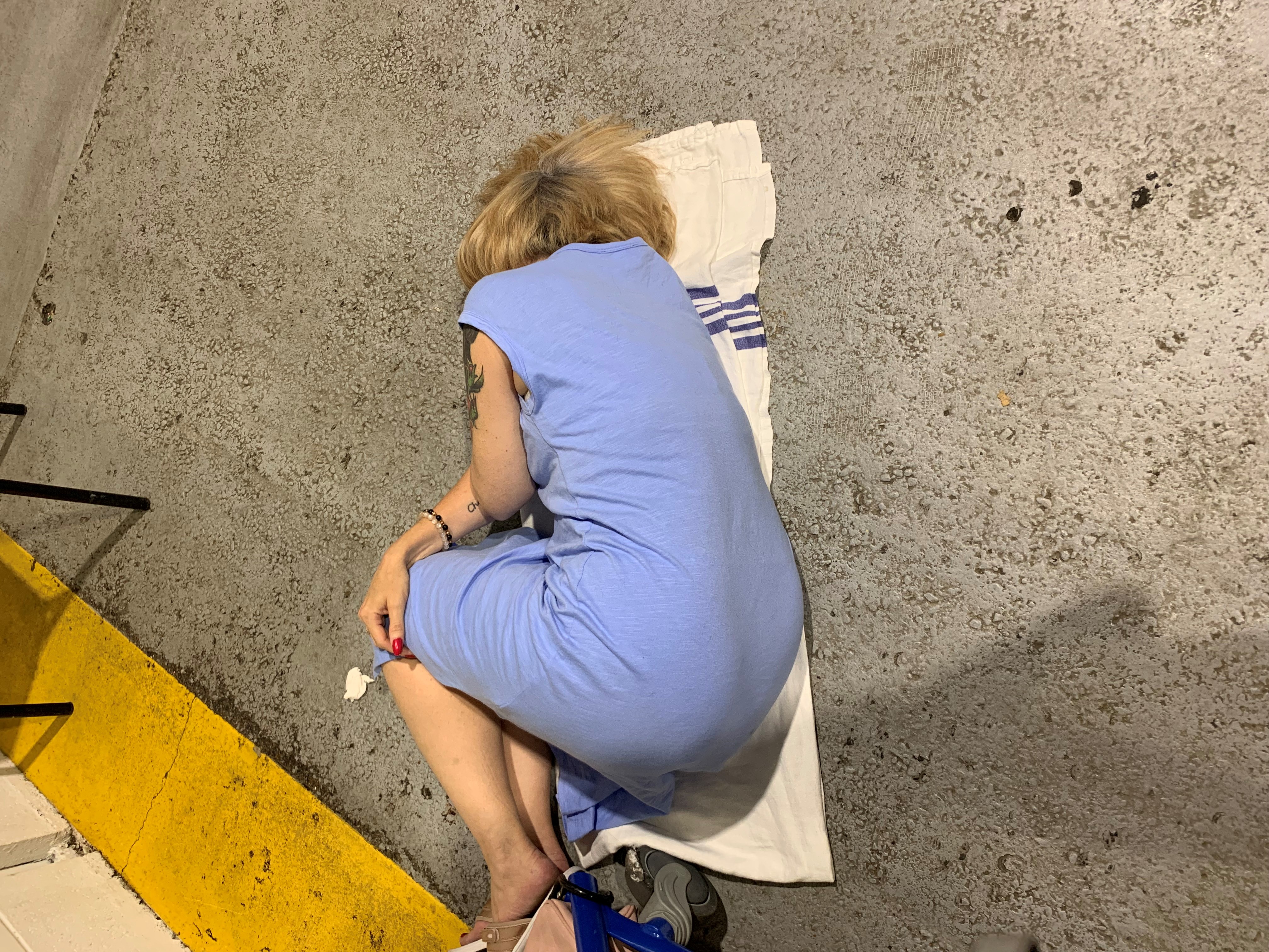 Trista Champagne, 47, laying on the floor of a waiting area at the Misericordia Community Hospital emergency department in Edmonton, Alta. on Sunday, Sept. 4, 2022.