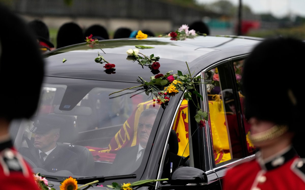 Flowers cover the hearse carrying the coffin of Queen Elizabeth II as it arrives outside Windsor Castle in Windsor, England, Monday, Sept. 19, 2022.