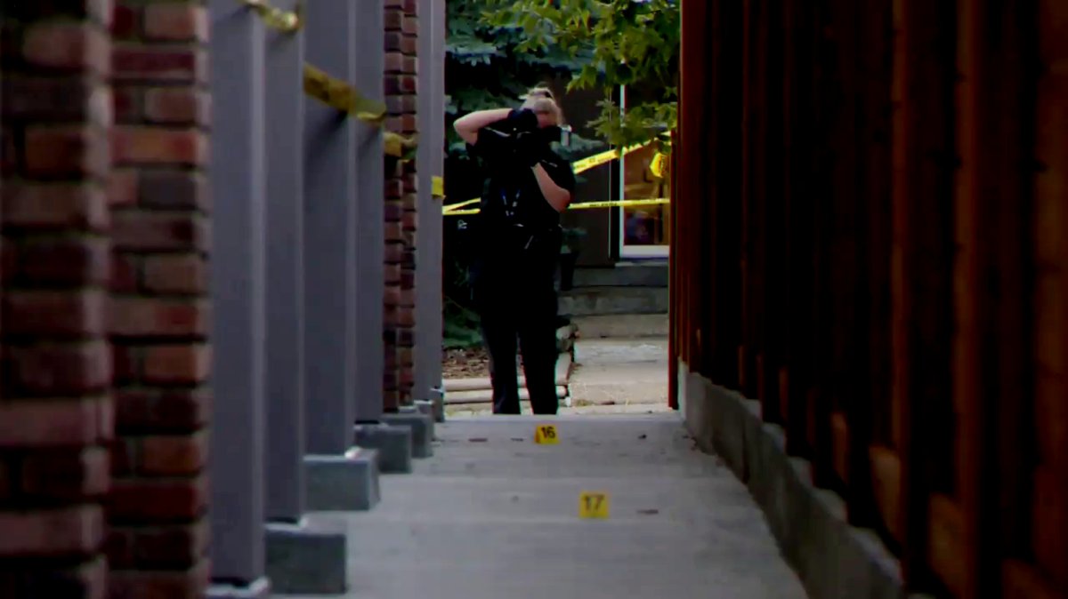 A Calgary Police Service investigators takes photos of evidence markers after an apparent shooting in South Calgary on Sept. 27, 2022.