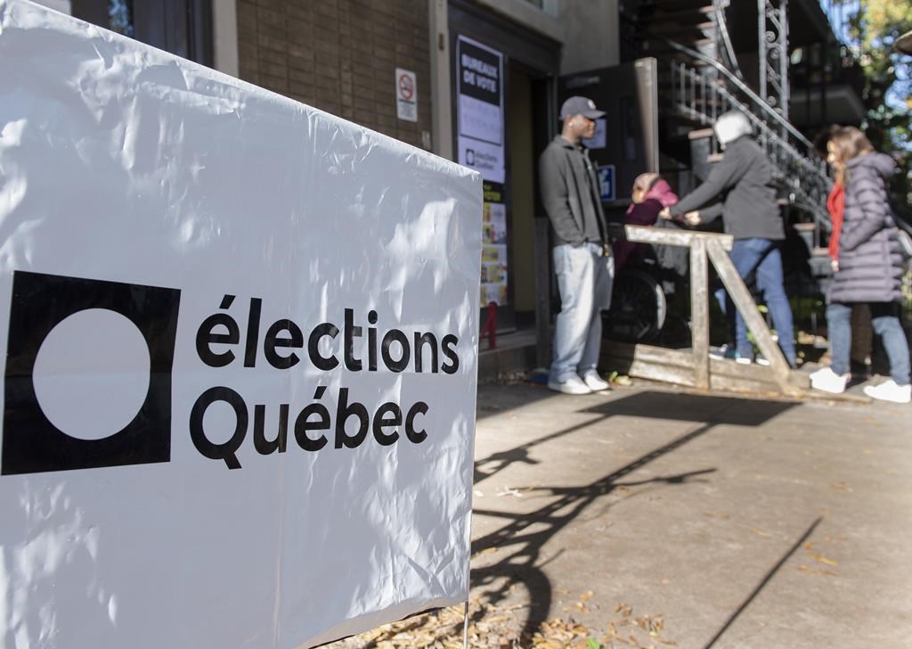 People wait in line to vote in Montreal on Quebec election day in, Oct. 3, 2022. Élections Québec announced had issued 38 statements of infraction, including a total of 78 charges, for violations related to the electoral signs of nine political parties.
