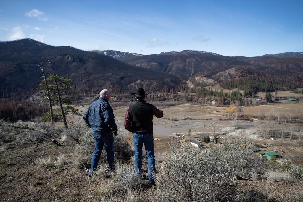 B.C. Minister of Public Safety Mike Farnworth, left, and Shackan Indian Band Chief Arnie Lampreau view damage to Shackan land caused by last summer's wildfires and November flooding west of Merritt, B.C., on Thursday, March 24, 2022. THE CANADIAN PRESS/Darryl Dyck.