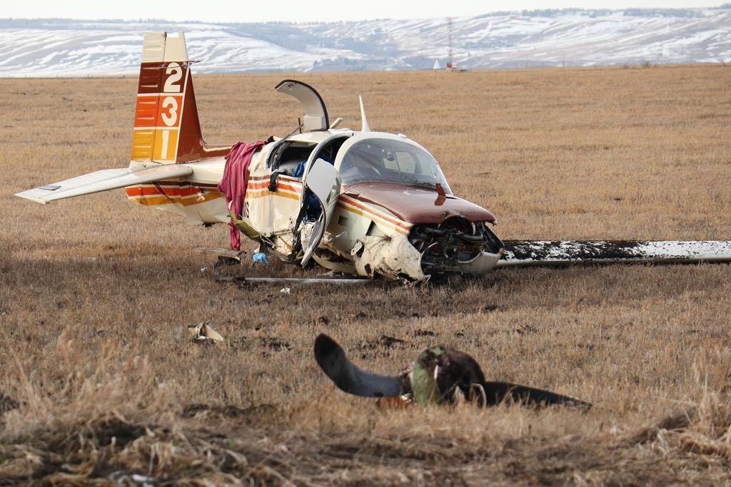 A small aircraft lies in a field next to the Trans-Canada Highway, within sight of the Springbank airport, after a crash west of Calgary, Friday, April 22, 2022.