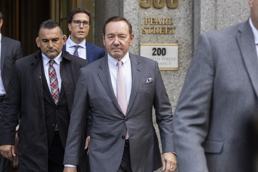 Kevin Spacey in a grey suit and pink tie.