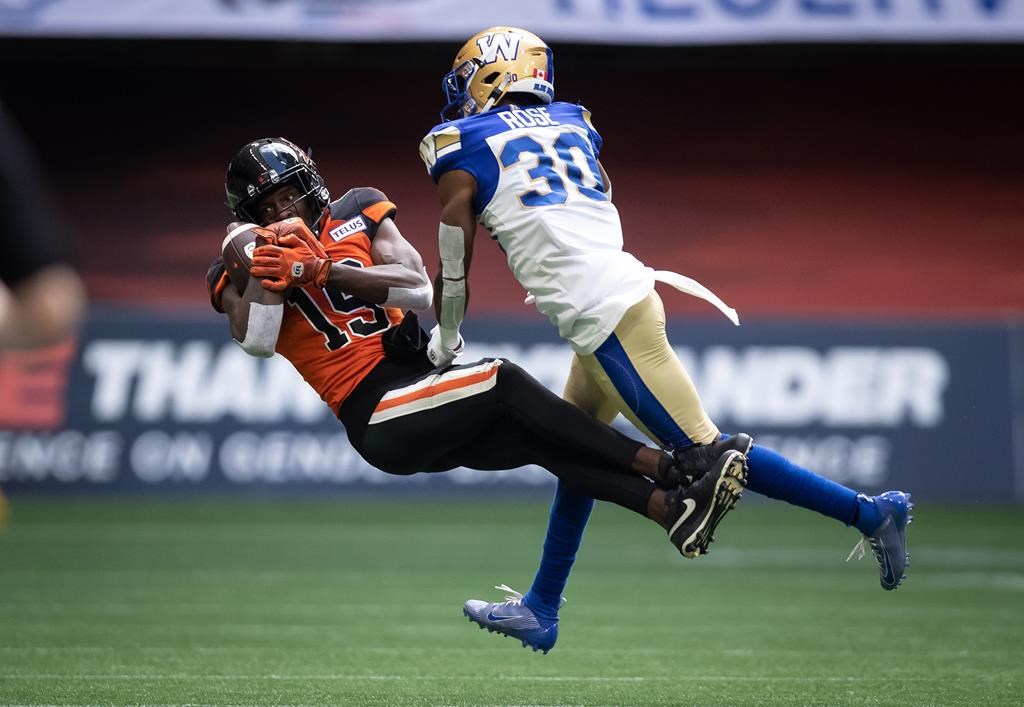B.C. Lions’ Dominique Rhymes, left, makes a reception as Winnipeg Blue Bombers’ Winston Rose defends during the first half of CFL football game in Vancouver, on July 9, 2022.