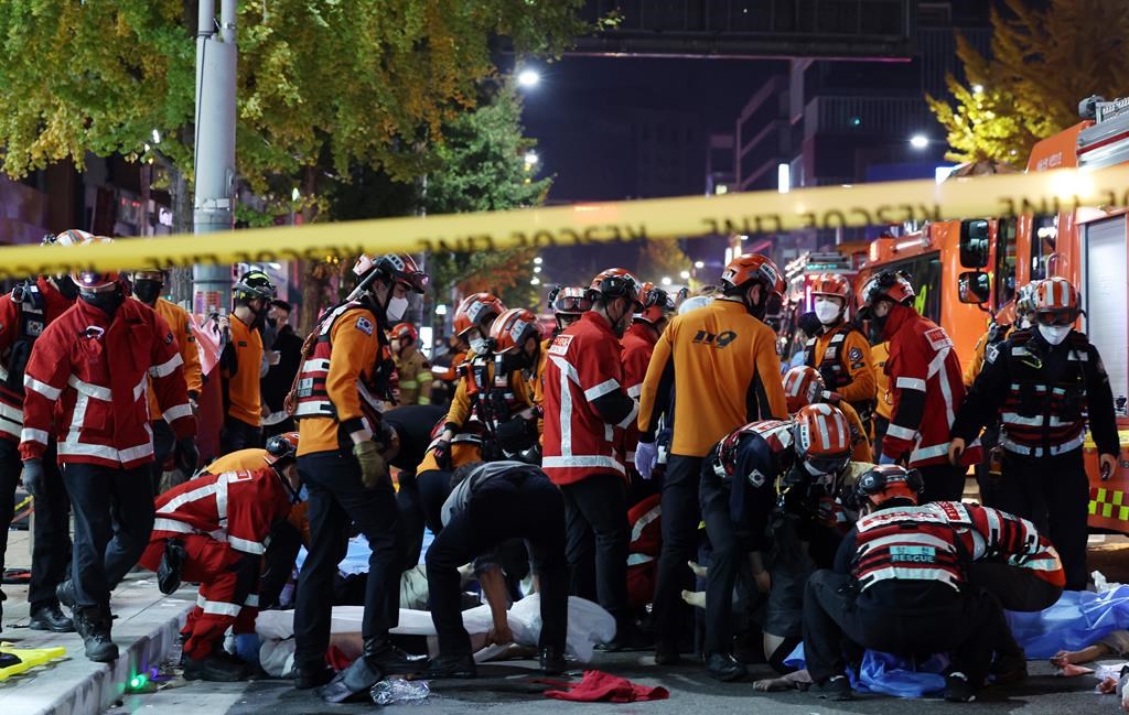 Rescue workers and firefighters work on the scene of a crushing accident in Seoul, South Korea, Saturday, Oct. 29, 2022. South Korean officials say dozens of people were in cardiac arrest after being crushed by a large crowd pushing forward on a narrow street during Halloween festivities in the capital Seoul. (Lee Ji-eun/Yonhap via AP)