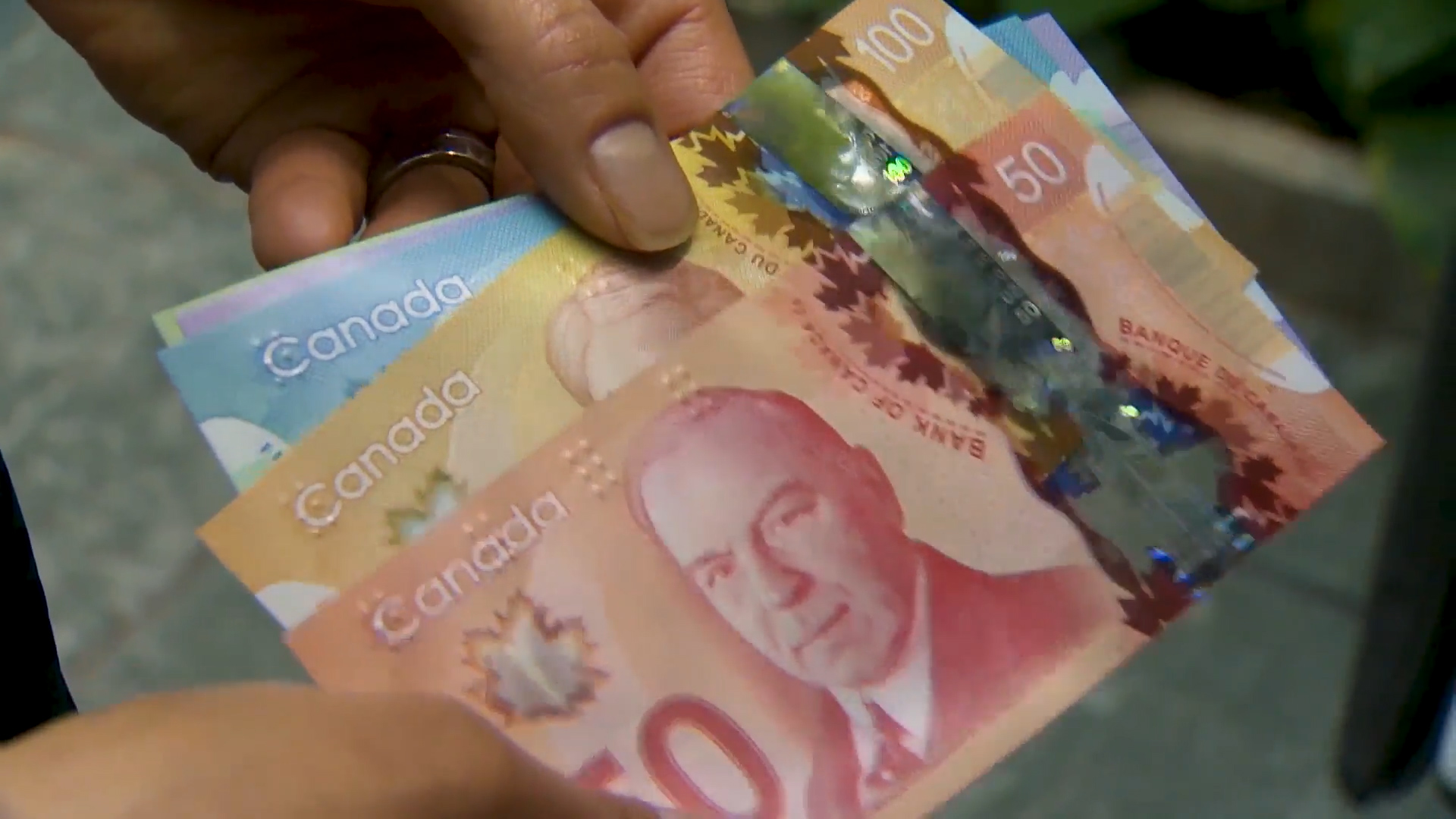 Someone holding $50 and $100 Canadian bank notes