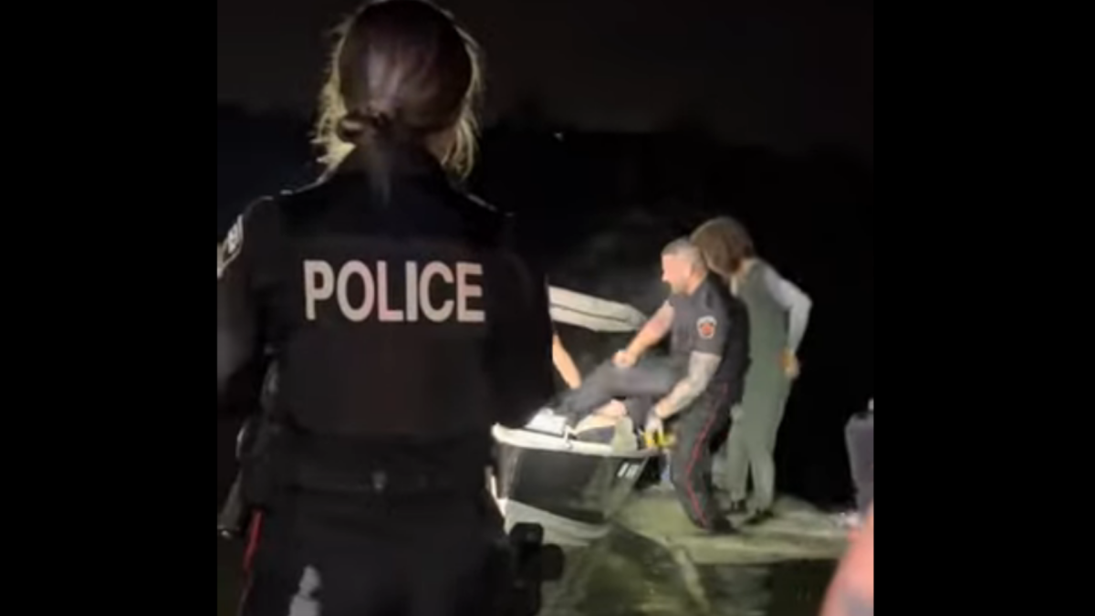 Fisherville, Ont. resident Shawn Farquharson and a Hamilton Police officer help remove a man from the water at Bayfront Park. Investigators say a car drove off a pier into Hamilton Harbour on Oct. 27, 2022.