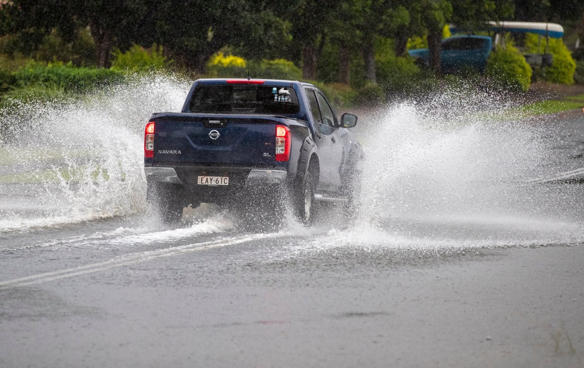 A vehicle plows through water on a flooded road at Port Stephens, 200 kilometers (120 miles) north of Sydney, Australia, Sunday, March 21, 2021.