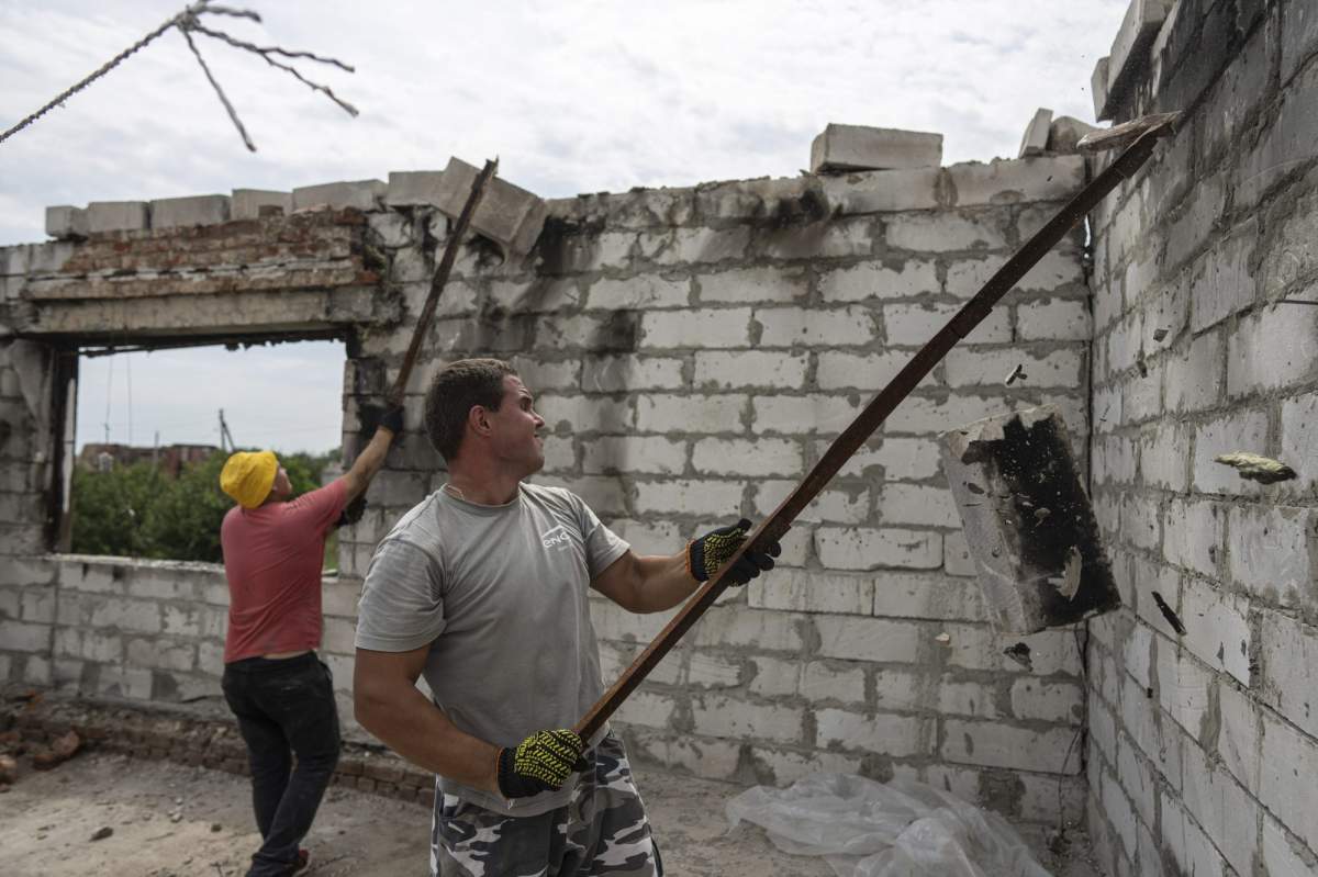 Volunteers clear rubble on the second floor of Zhanna and Serhiy Dynaeva’s house which was destroyed by Russian bombardment, in the village of Novoselivka, near Chernihiv, Ukraine, on Saturday, Aug. 13, 2022. Residents in many heavily-damaged areas in Ukraine have set up their own initiatives to rebuild homes before the winter as international organizations rush aid to Ukraine to help with the reconstruction effort. (AP Photo/Evgeniy Maloletka)