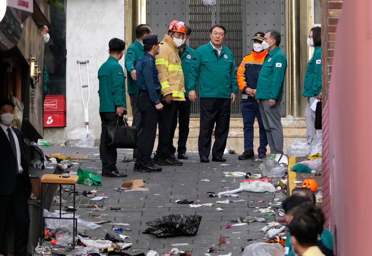 South Korean President Yoon Suk Yeol, center, is briefed at the scene where dozens of people died and were injured in Seoul, South Korea, Sunday, Oct. 30, 2022, after a mass of mostly young people celebrating Halloween festivities became trapped and crushed as the crowd surged into a narrow alley. 