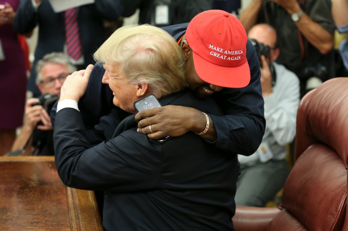 Kanye West hugs Donald Trump while wearing a red MAGA hat.