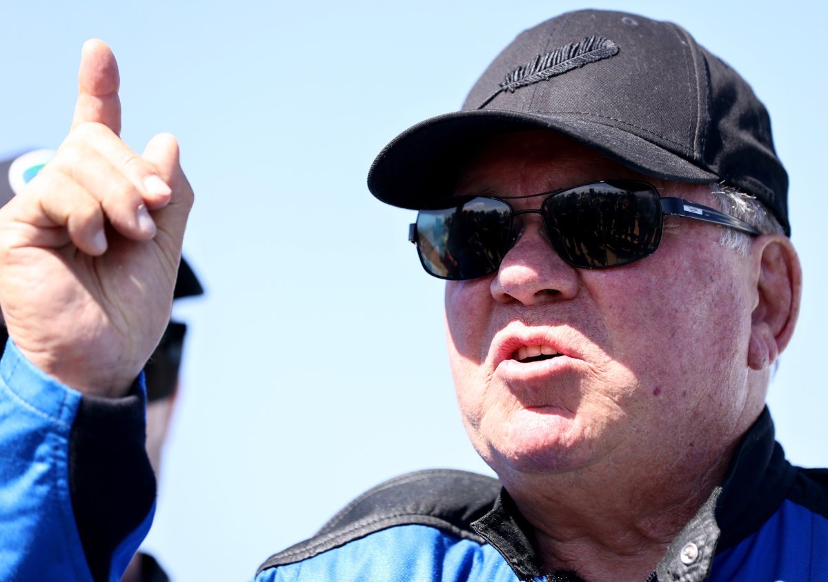 William Shatner pointing his finger. He is wearing a black ball cap and dark, tinted sunglasses.