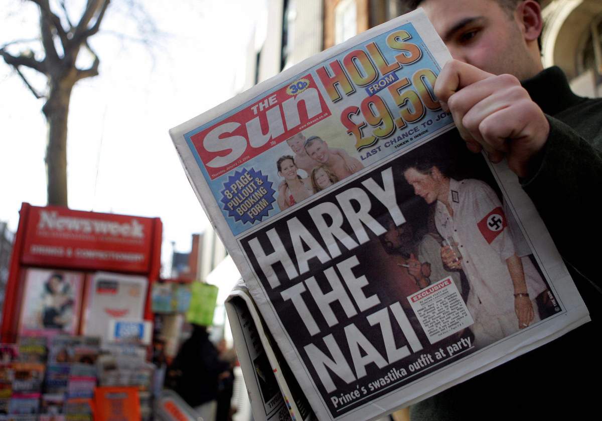 A man reads a copy of "The Sun." Prince Harry is wearing a Nazi solider costume on the front page.