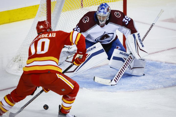 Colorado Avalanche goalie Pavel Francouz, right, guards the net as Calgary Flames forward Jonathan Huberdeau chases the puck during third period NHL hockey action in Calgary, Thursday, Oct. 13, 2022.