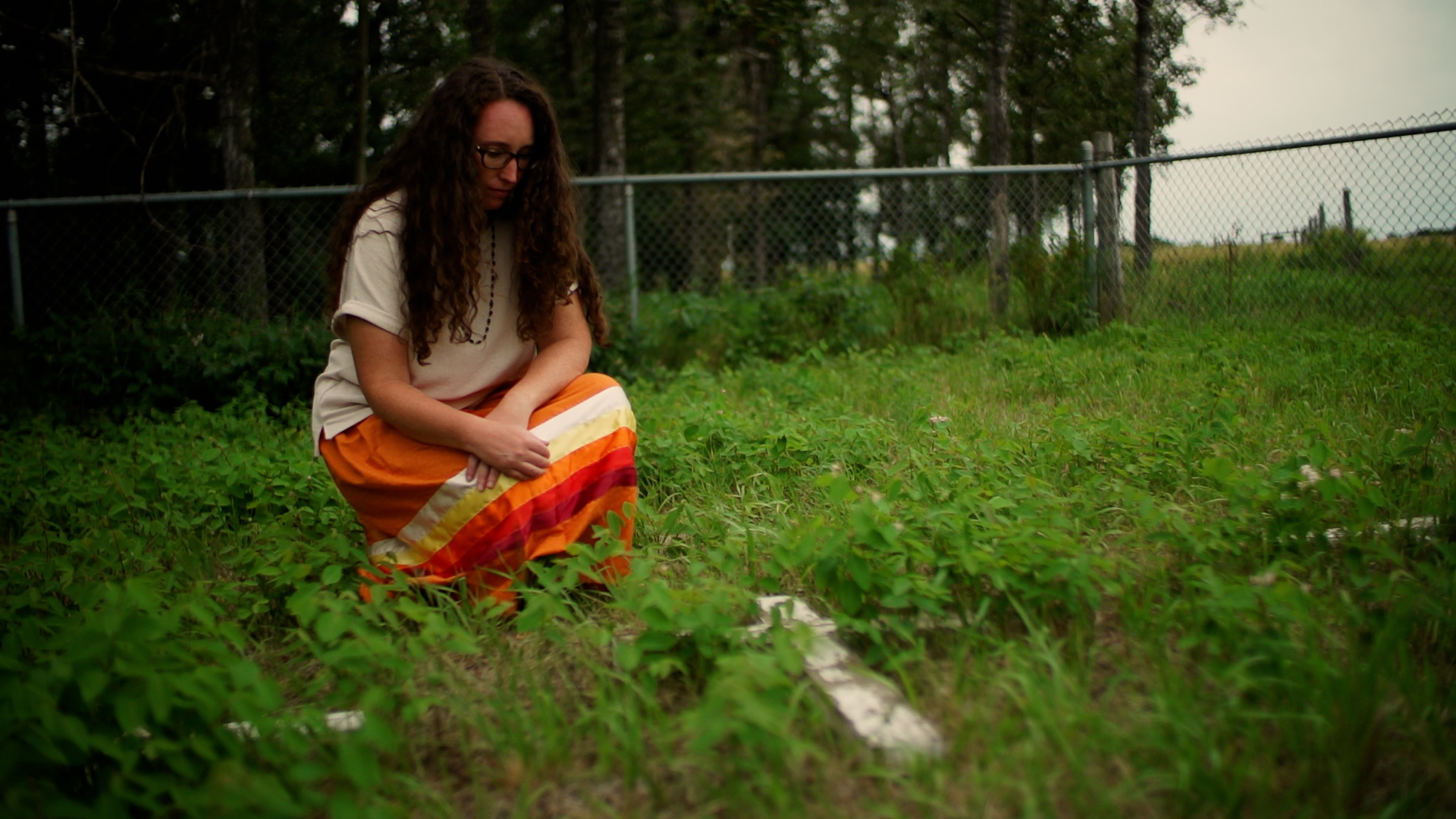 Katherine Nichols kneels by one of the wooden crosses at the North Hill Burial Grounds.