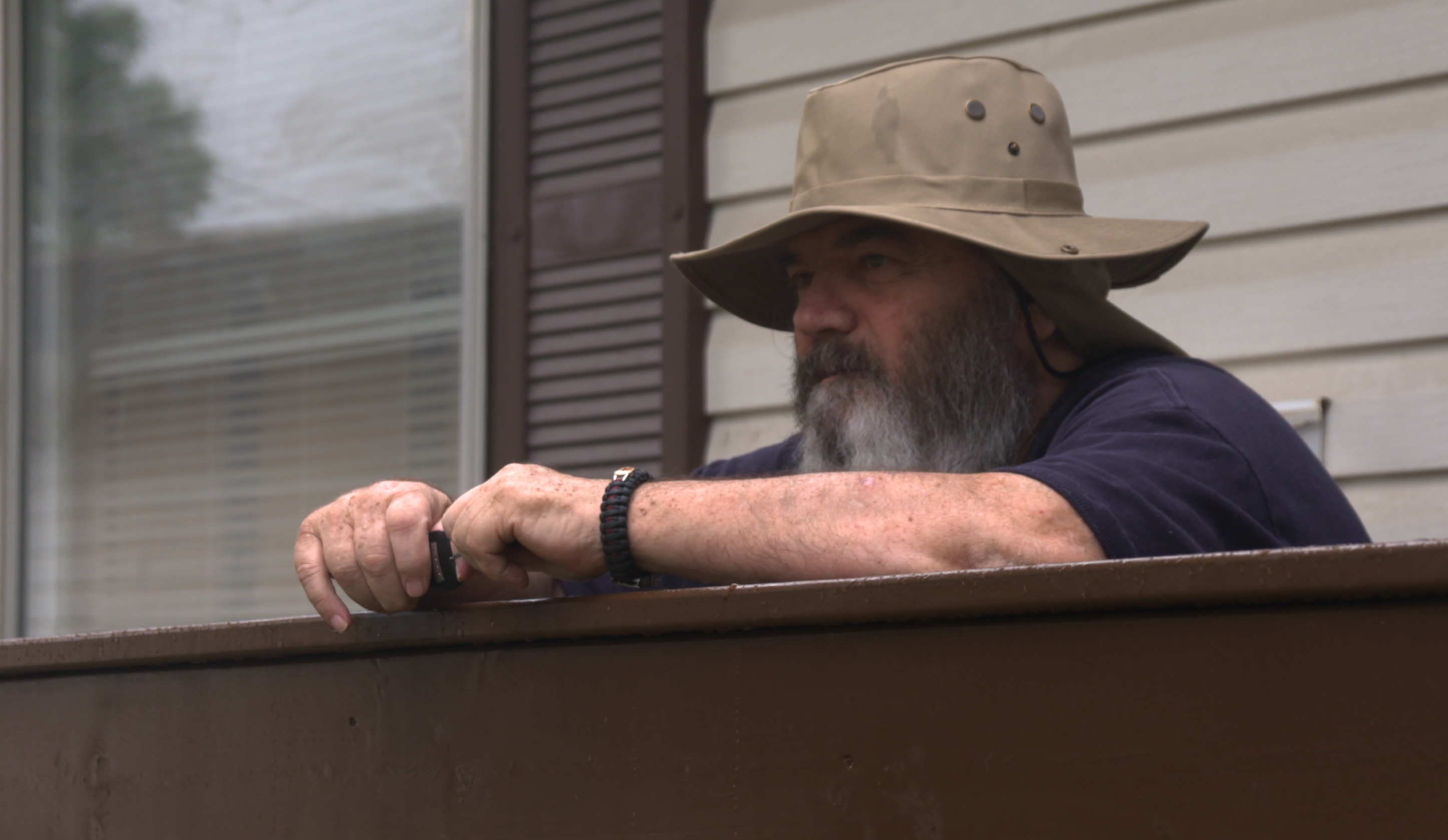 A man in a hat gazes out over a railing