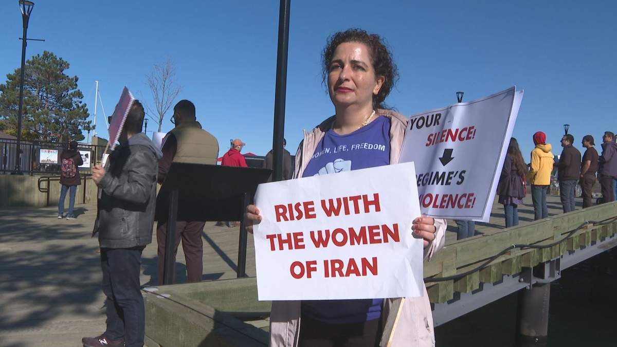 Protester holding a sign that reads "rise with the women of Iran"