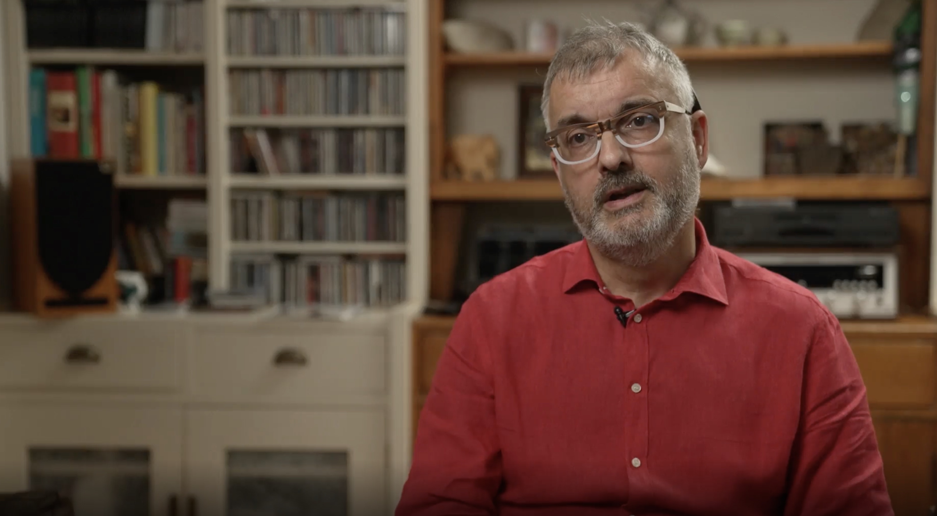 A man with glasses wearing a red shirt inside a library