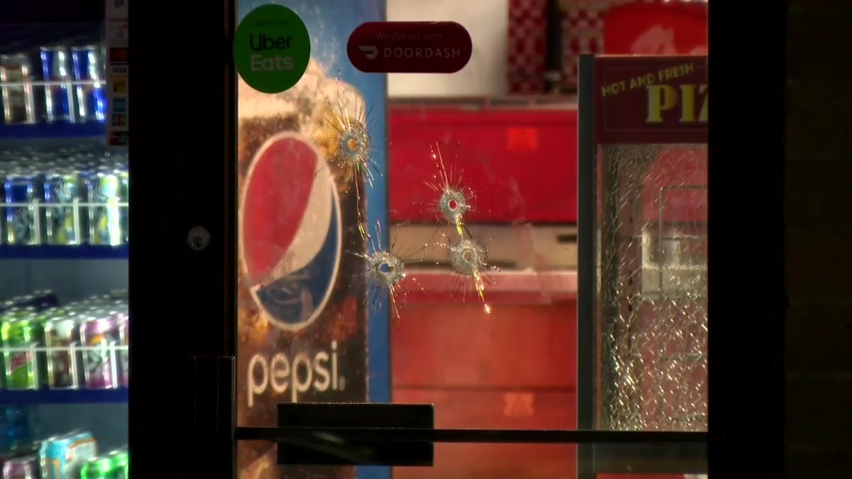 Bullet holes in the glass door of TJ's Pizza in the northwest after Calgary police said there was a shooting on Oct. 20, 2022.