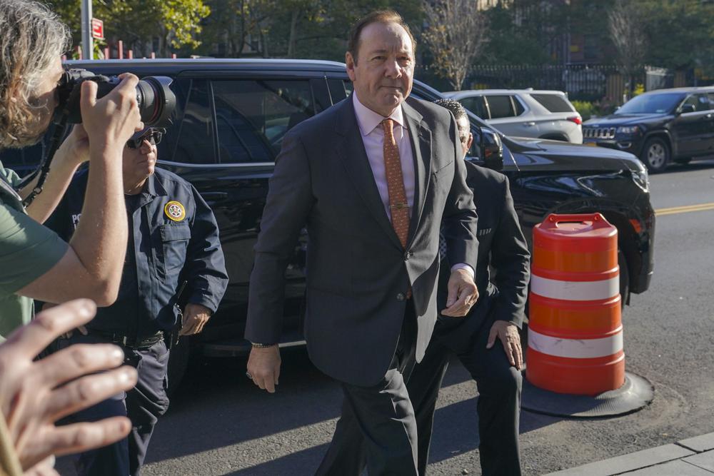 Kevin Spacey walking into the courthouse from a car. He is wearing a black suit.