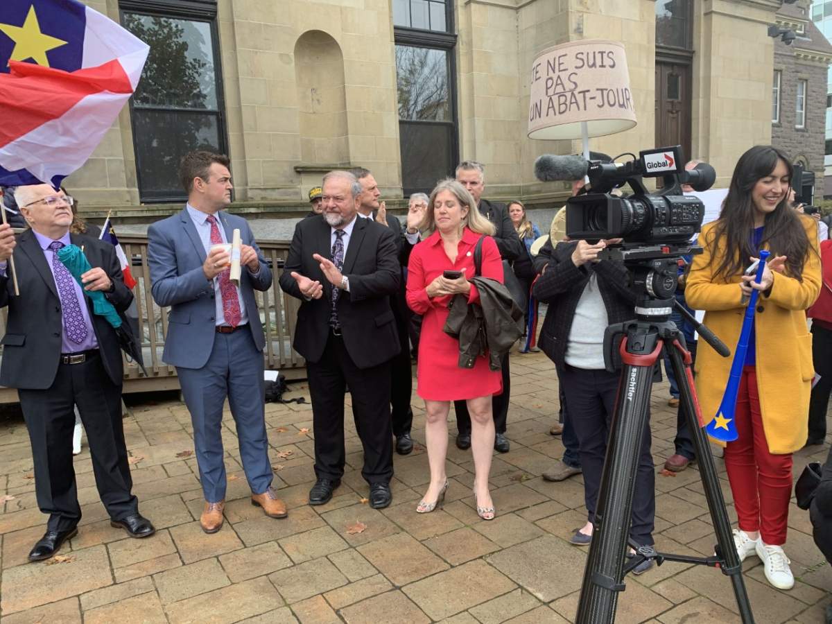 Liberal MLAs standing in support of the cultural and linguistic communities with Francine Landry holding a lampshade that says “I’m not a lampshade.”