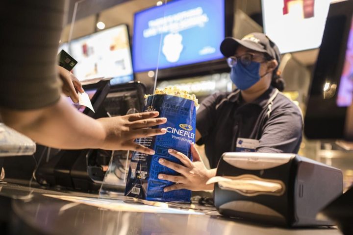 A Cineplex employee serves customers popcorn and other snacks at a Cineplex theatre in Toronto on Wednesday, Aug. 26, 2020. 