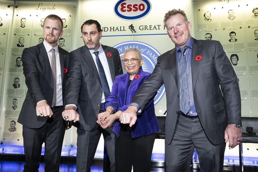 Daniel Sedin, left to right, Roberto Luongo, Herb Carnegie’s daughter, Bernice Carnegie, and Daniel Alfredsson pose with their rings during a ceremony to celebrate the latest inductees into the ‘Hockey Hall of Fame’ at an event in Toronto, Friday, Nov. 11, 2022.