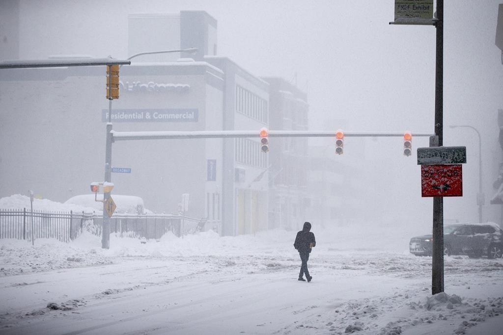 A person crosses Ellicott Street as snow falls Friday, Nov. 18, 2022, in Buffalo, N.Y. 