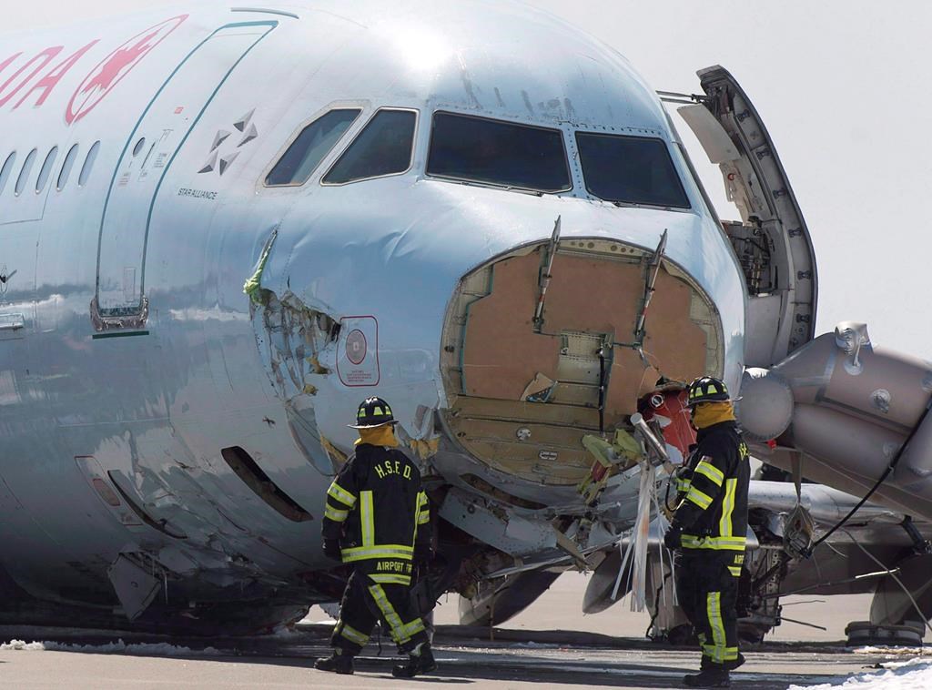 Airport firefighters work at the crash site of Air Canada AC624 that crashed early Sunday morning during a snowstorm, at Stanfield International Airport in Halifax on March 30, 2015. THE CANADIAN PRESS/Andrew Vaughan.