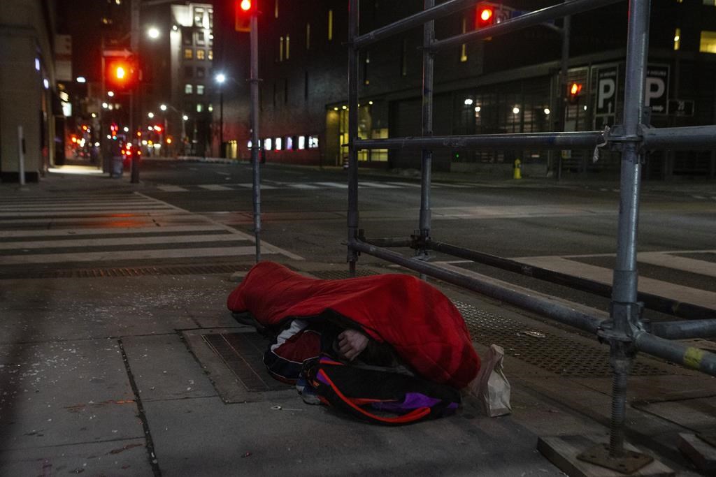 A homeless man sleeps on the street in Toronto on Friday, March 11, 2022. Some people experiencing homelessness say they don't know where they'll go once they're kicked out of a Toronto COVID-19 shelter hotel in early December and community workers are equating the timing of its closing to a death sentence out in the cold. 