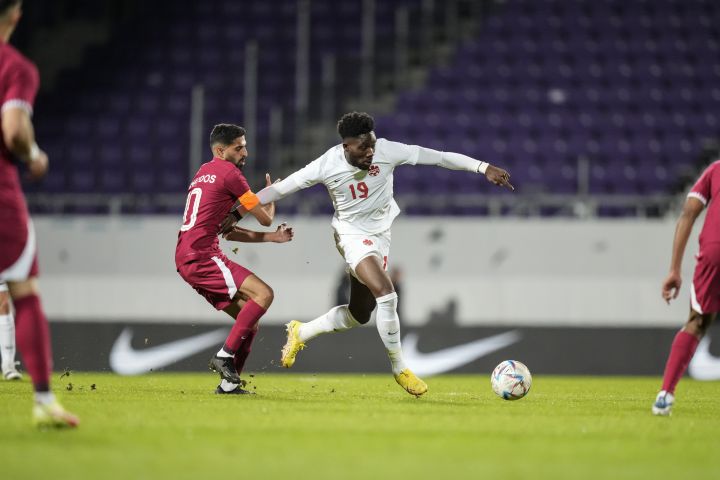 Canada’s Alphonso Davies, right, is challenged by Qatar’s Mohammed Muntari during the international friendly soccer match between Qatar and Canada, at the Viola Park stadium in Vienna, Austria, Friday, Sept. 23, 2022.