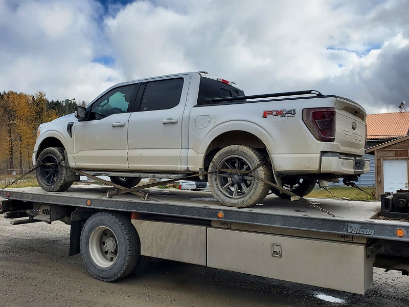 The white Ford F150 pickup truck on the back of a flat deck tow truck after being seized by police.