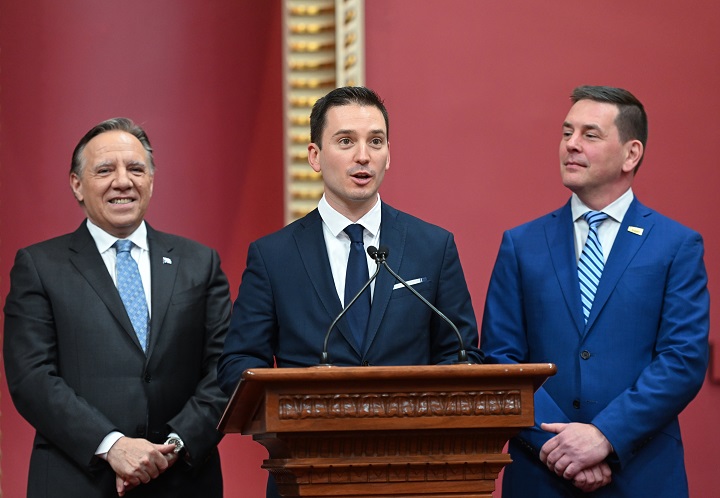 Coalition Avenir Québec MNA Simon Jolin-Barrette swears allegiance to King Charles III as he is sworn in, Tuesday, October 18, 2022 during a ceremony at the legislature in Quebec City. Quebec Premier François Legault, left, and National Assembly secretary general  Siegfried Peters, look on.   