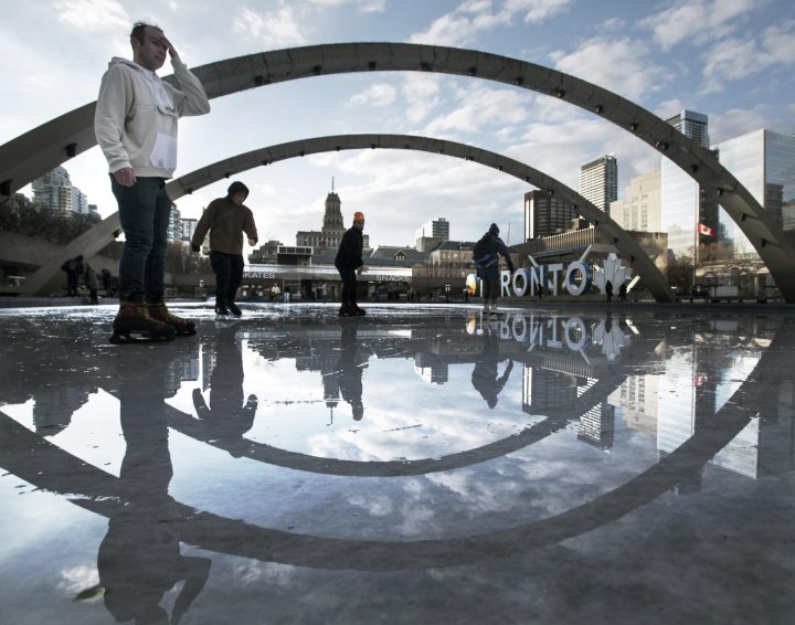 Skaters are framed by arches as theyíre reflected in the wet ice as they take to the rink at Nathan Phillips Square on Dec 6, 2021. 