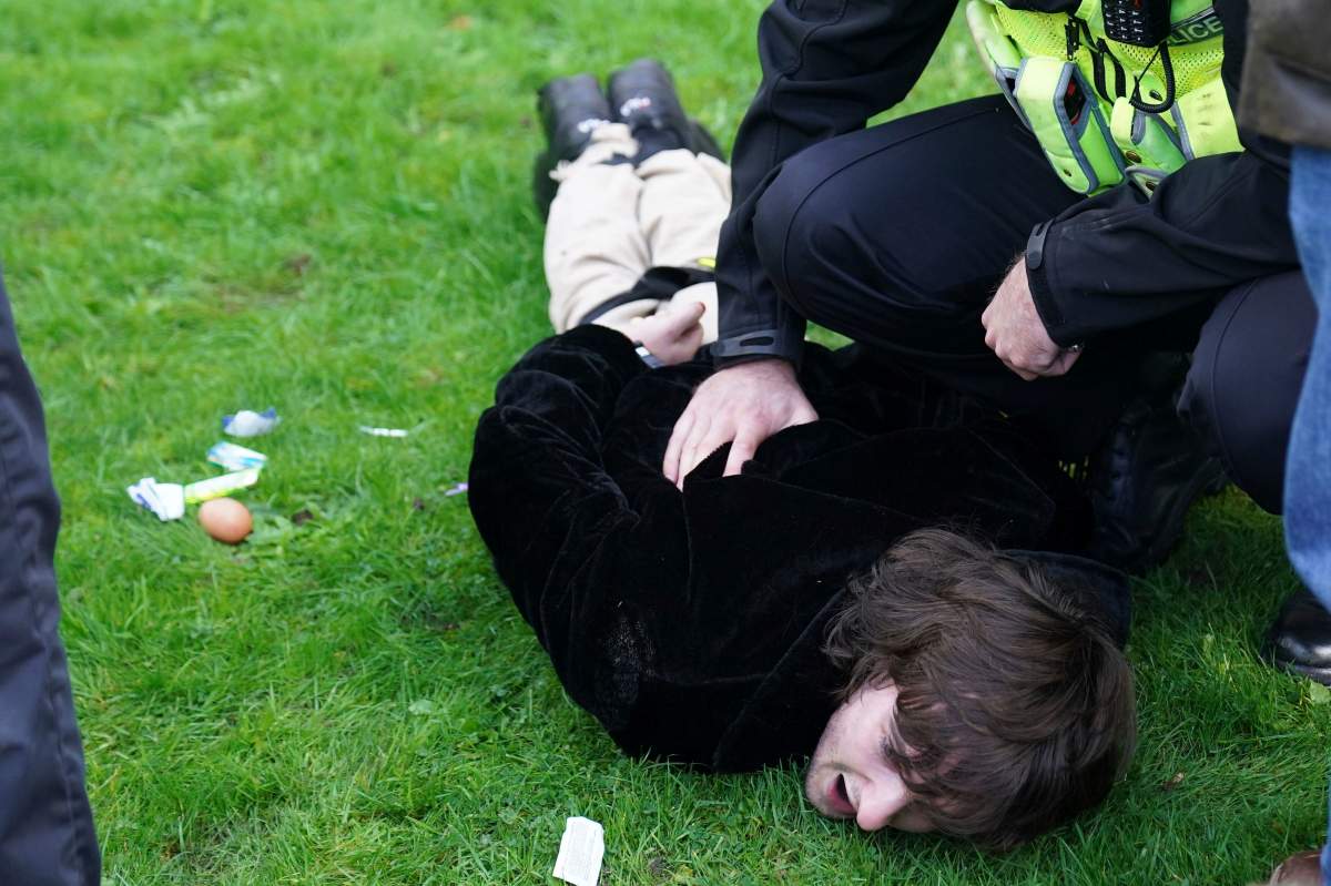Police empty contents, including an unthrown egg, left, from the pockets of a protester, as they detain him for throwing eggs at Britain's King Charles III and Camilla, the Queen Consort, as they arrived for a ceremony at Micklegate Bar, where the Sovereign is traditionally welcomed to the city, in York, England, Wednesday Nov. 9, 2022.