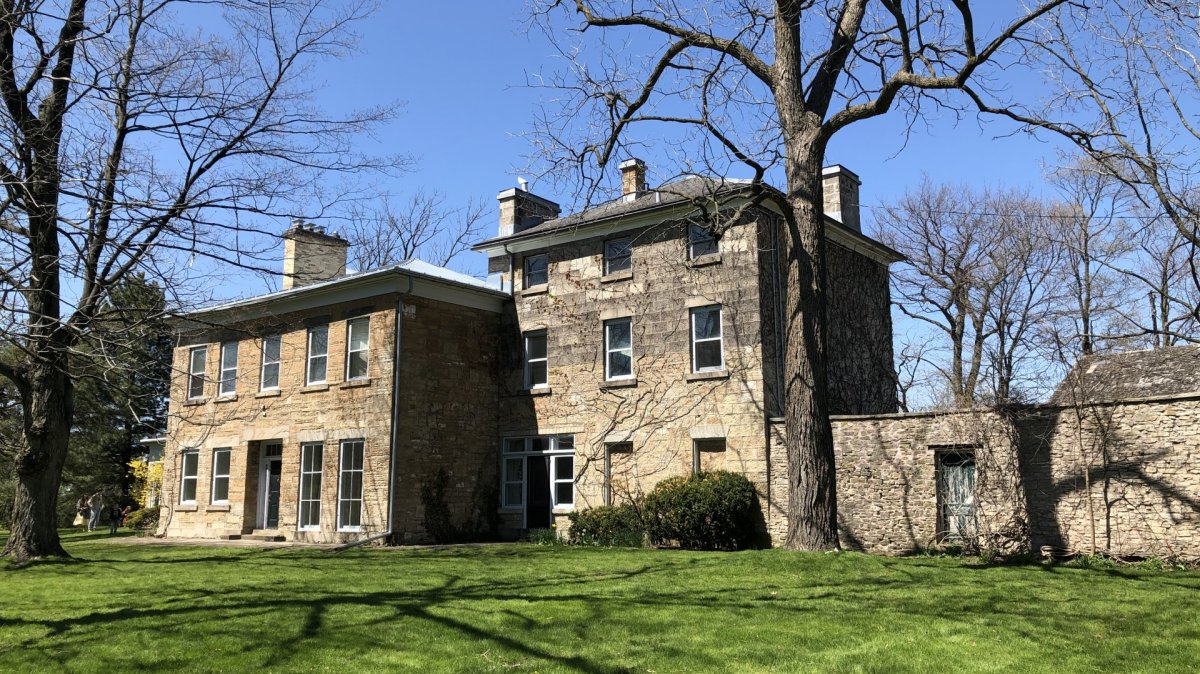 Chedoke Estate, a 186-year-old heritage property that stands atop Hamilton's mountain brow. It's a large multi-level building made out of grey stone, with plenty of windows and large trees framing the house.