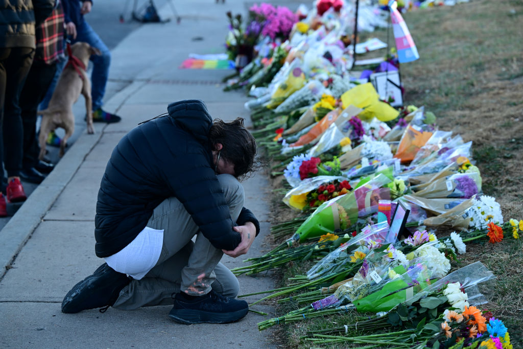 his head on his knees as he pays his respects at a makeshift memorial near Club Q on November 20, 2022 in Colorado Springs, Colorado.