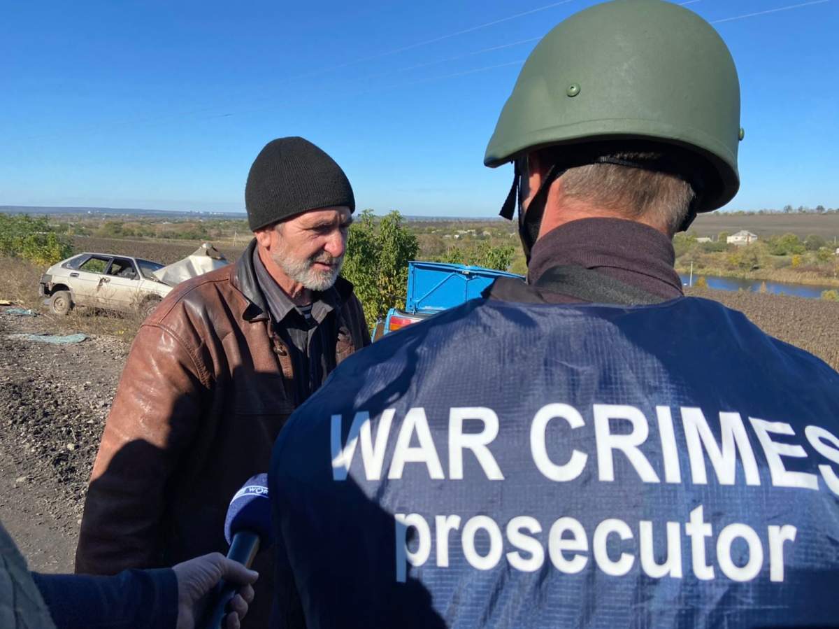 Ukrainian war crimes investigator speaks to survivor Mykola Bondarenko at scene of convoy attack in Kharkiv region.