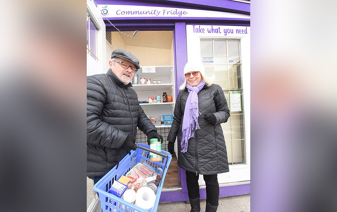 Dave Cobeil and wife Allison Howard stock the shelves of their Penticton Community Fridge and Pantry outside the Elk's Lodge this week.