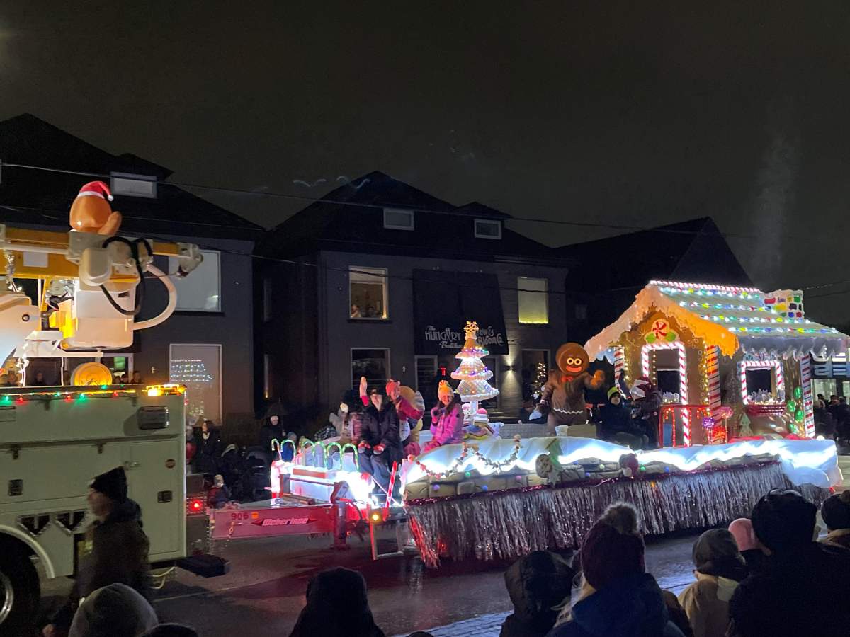 Gingerbread man waves to the crowd from out front of his house.