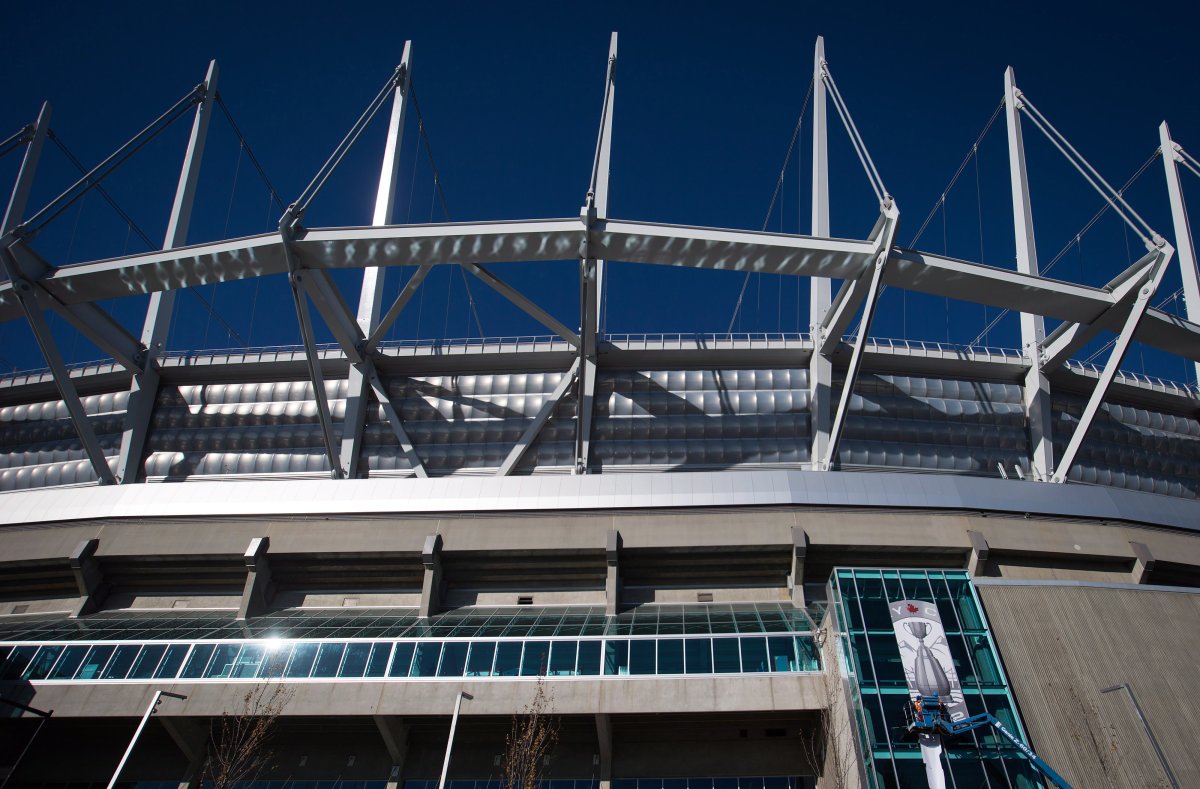 B.C. Place in Vancouver, seen here in 2014 as workers hoist a banner, will host the 2024 Grey Cup, the CFL announced on Thursday. The stadium last hosted the league’s championship game in 2014.