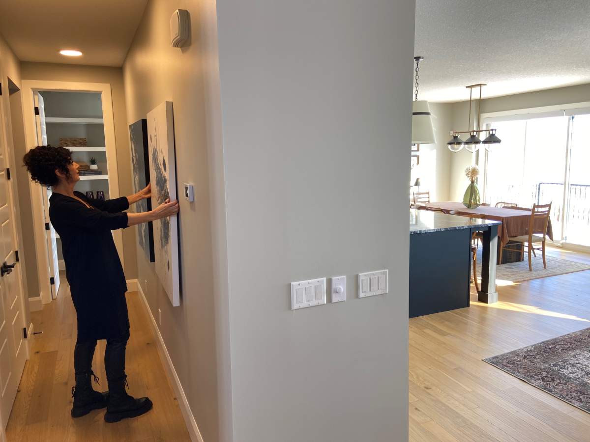 Michelle Krüger hanging one of her finished pieces in a showhome.