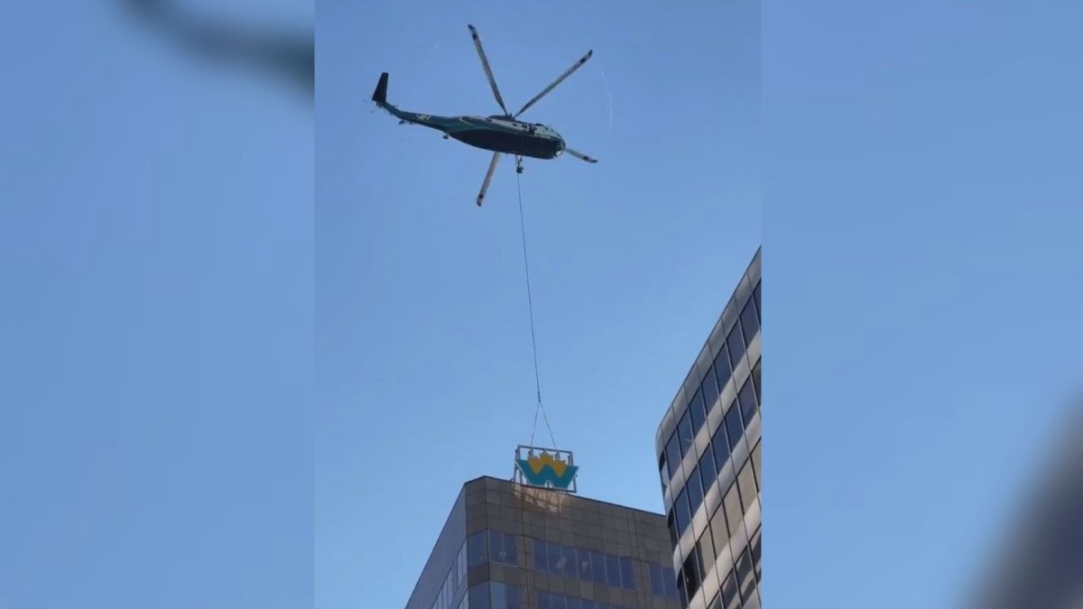 A helicopter installs a new LED sign on the Canadian Western Bank building in downtown Vancouver on Sunday, Nov. 13, 2022.