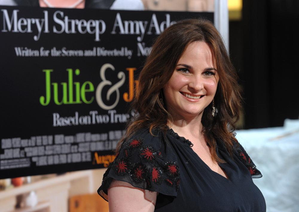 Julie Powell smiling in front of a 'Julie and Julia' poster.