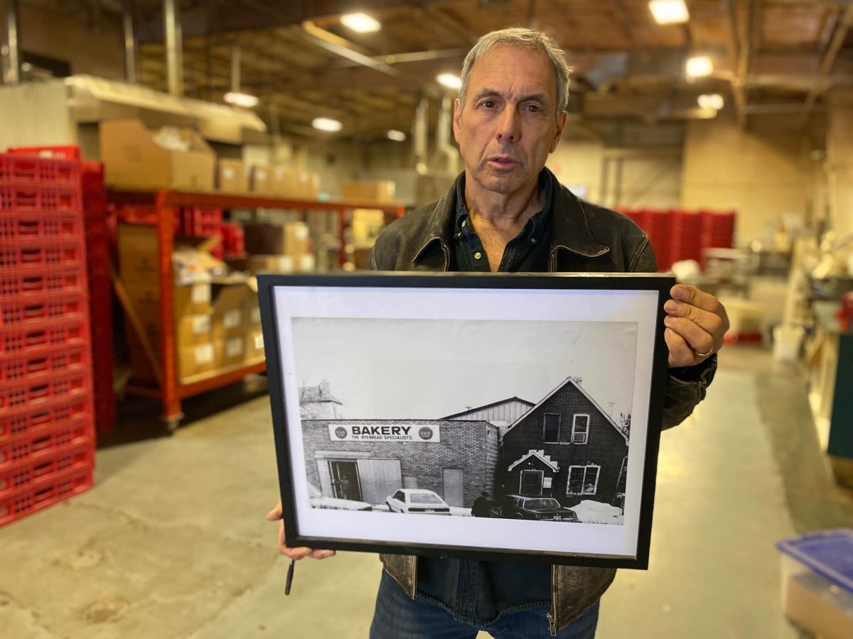 Ross Einfeld hold a black and white photo of the old Kub Bakery location