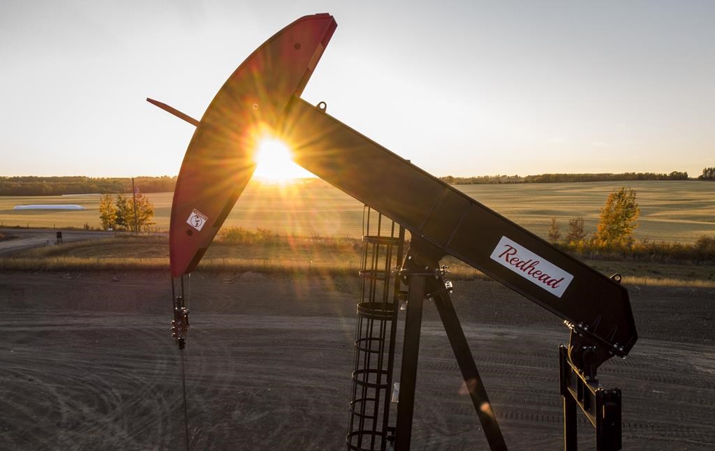 A pumpjack draws out oil and gas from a well head as the sun sets near Calgary, Alta., Sunday, Oct. 9, 2022.