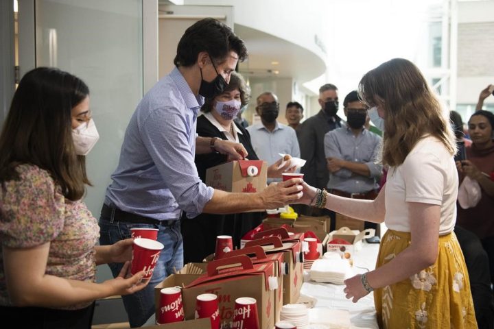 Prime Minister Justin Trudeau pours a cup of hot chocolate as he visits residents affected by a major storm at a community centre set up to provide food, showers, wifi and device charging in Ottawa, Thursday, May 26, 2022.