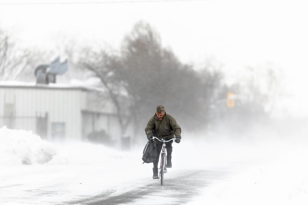 FILE - A man rides his bike down the street in Fort Erie, Ont., during an early winter storm on Saturday, Nov. 19, 2022.