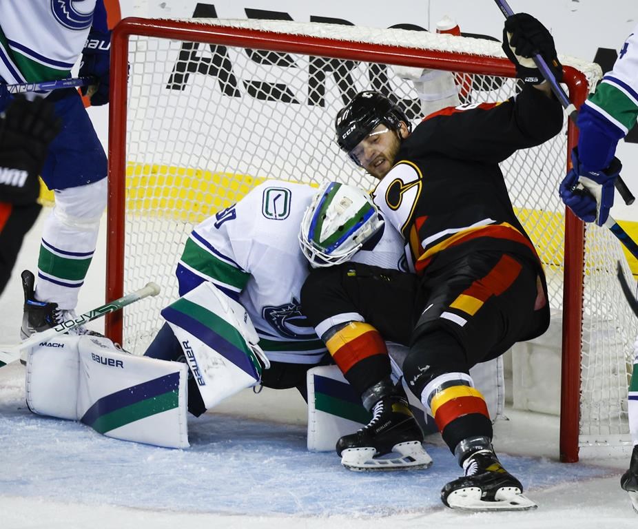Vancouver Canucks goalie Spencer Martin, left, falls back as Calgary Flames forward Radim Zohorna crashes into him during second period NHL hockey action in Calgary, Wednesday, Dec. 14, 2022.