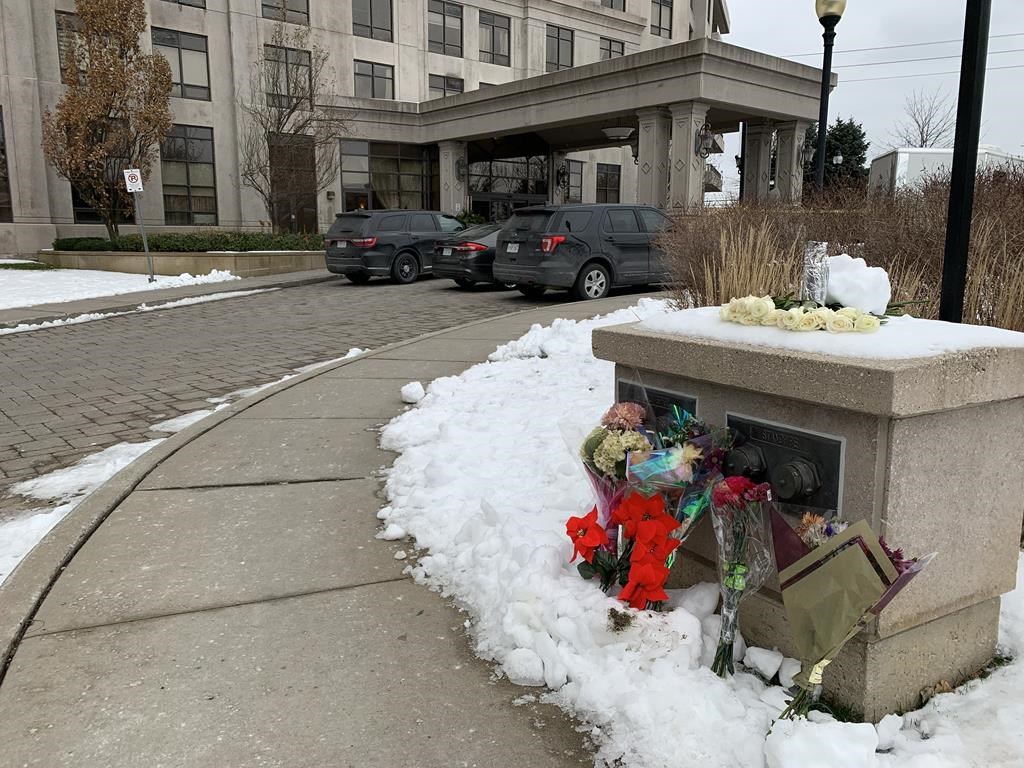 Floral tributes are shown outside a condo building in Vaughan, Ont., Tuesday, Dec. 20, 2022. Heartfelt tributes are pouring in for the five people who were killed over the weekend after a 73-year-old man went door to door gunning down his victims in a Toronto-area condo. THE CANADIAN PRESS/Fakiha Baig.